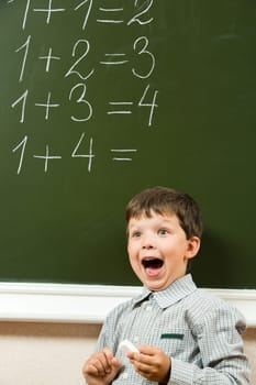 Portrait of happy boy screaming before blackboard with sums on it during lesson