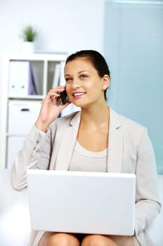 Image of young employer speaking on the phone with laptop on her knees