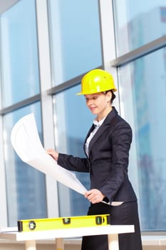 A young woman architect in helmet examining a plan