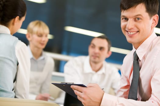 Portrait of happy businessman smiling at camera on background of working employees