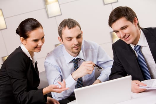 Portrait of executive employees looking at laptop monitor and discussing new project during meeting