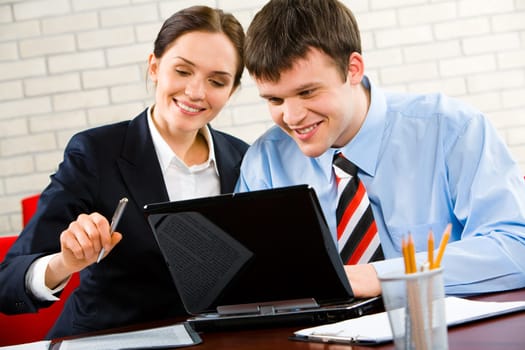 Business man and woman sitting at the table and looking at the laptop
