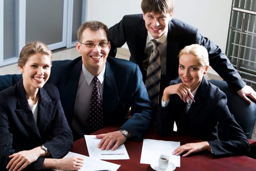 Large group of young businessmen looking at camera gathered together around the table