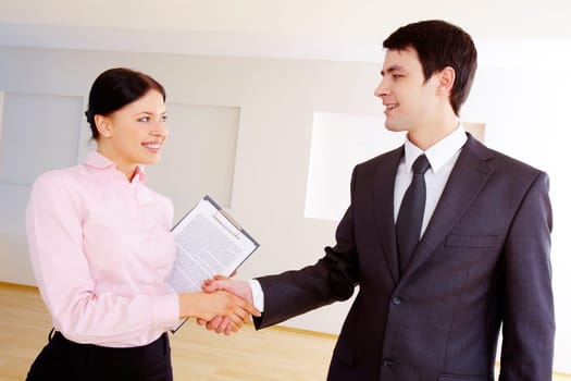 Photo of happy partners handshaking after signing contract