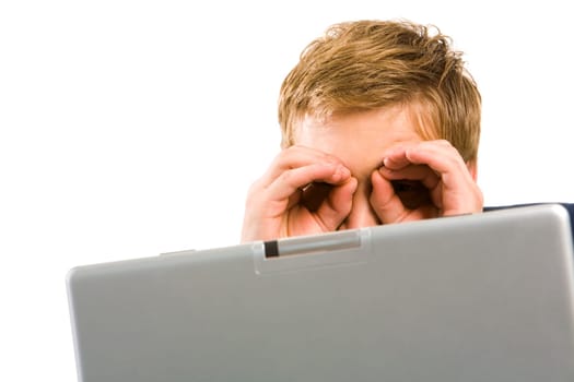 Portrait of businessman with his hands by eyes while sitting in front of laptop