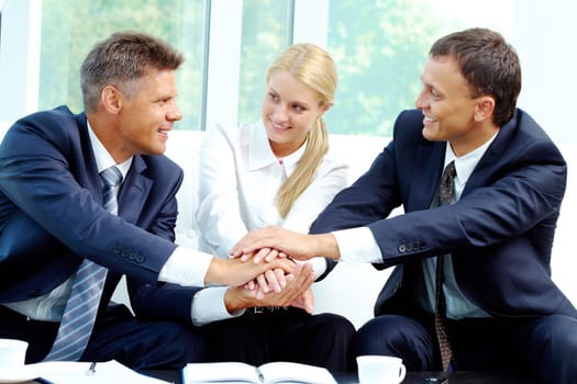 Portrait of smiling co-workers making pile of hands and looking at each other