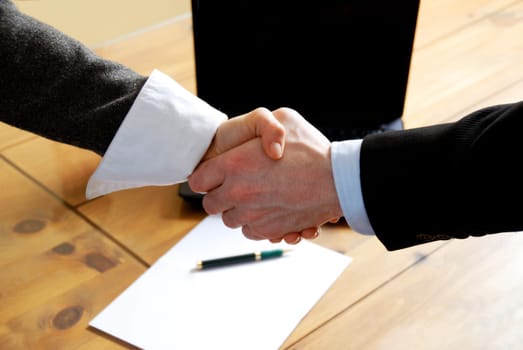 man and woman shaking hands in front of laptop