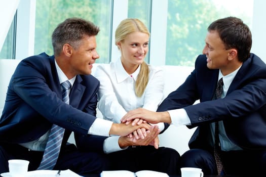 Portrait of smiling co-workers making pile of hands and looking at each other
