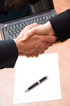 2 hands shaking with a blank contract and pen