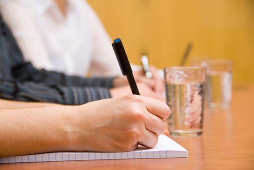 close up of some hands writing in a meeting room