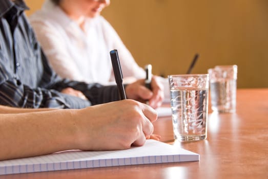 close up of some hands writing in a meeting room