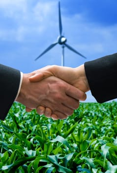 shaking hands with a wind mill in the background