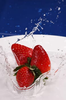3 strawberries splashing in water