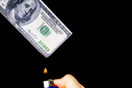 putting fire to a us banknote on black background