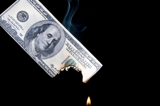 putting fire to a us banknote on black background