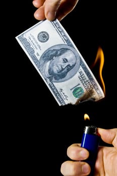 putting fire to a us banknote on black background