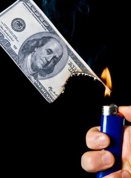 putting fire to a us banknote on black background