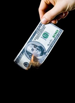 putting fire to a us banknote on black background