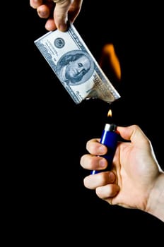 putting fire to a us banknote on black background