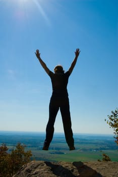 Woman on the top of a mountain jumping