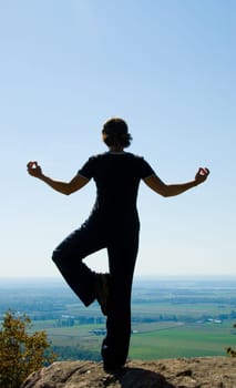 Woman on the top of a mountain doing yoga
