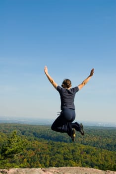 Woman on the top of a mountain happy jumping
