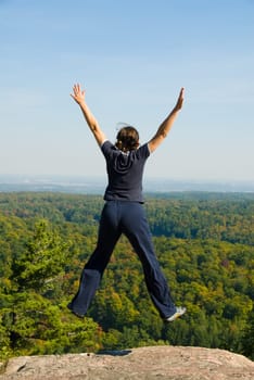 Woman on the top of a mountain happy jumping