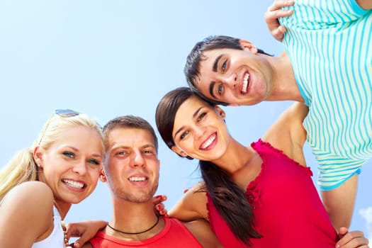 Portrait of four hugging friends looking at camera and smiling