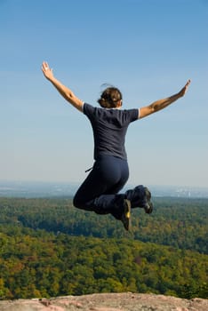 Woman on the top of a mountain happy jumping
