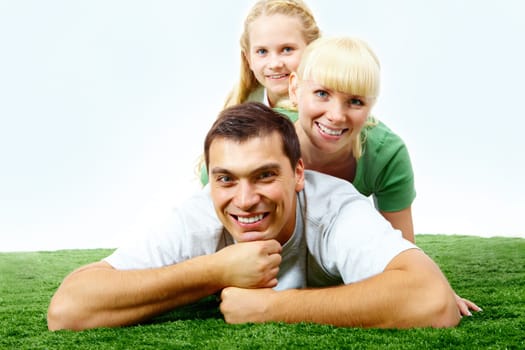 Portrait of happy family lying on grass and looking at camera