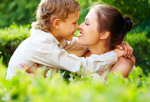 Happy boy and his mother touching by noses and looking at each other