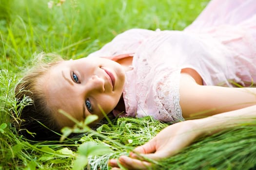 Close-up of young female lying on fresh grass and looking at camera during rest
