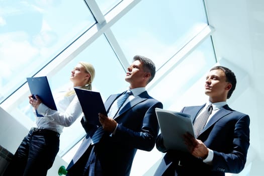 Row of business team holding clipboards and standing in the office
