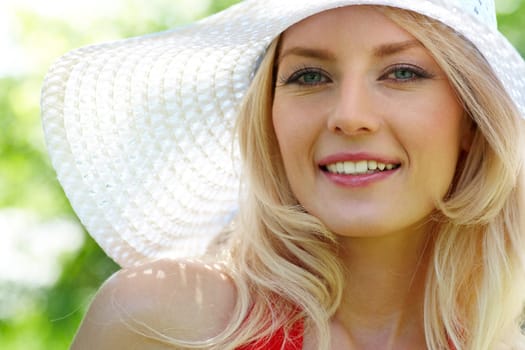 Pretty young lady in elegant hat smiling while looking at camera