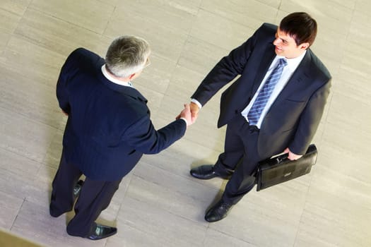 High angle view of two businessmen shaking hands after signing contract