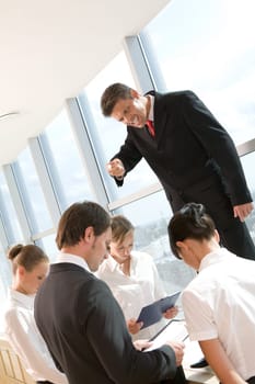 Angry ceo shouting at his employees surrounding him at meeting