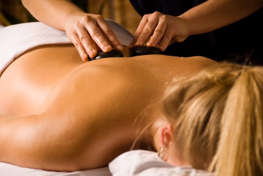 therapist giving a hot stone massage cute blond