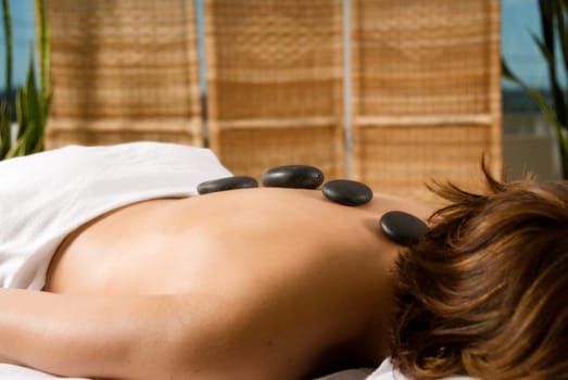 woman in a day spa with hot stones on her back