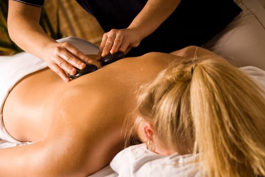 therapist giving a hot stone massage to woman
