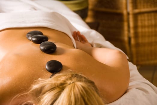 blond woman at a day spa with hot stones