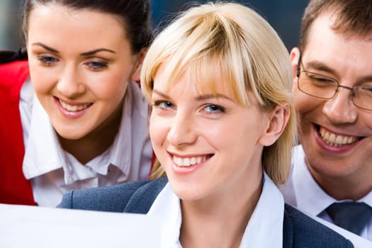 Photo of three smiling business peoples faces with a blonde young successful business lady at the front