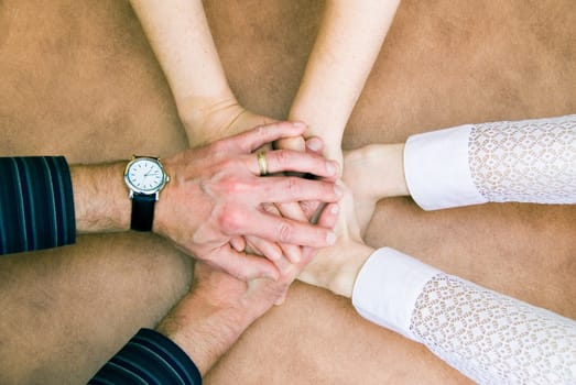 six hands clasp together in symbol of unity