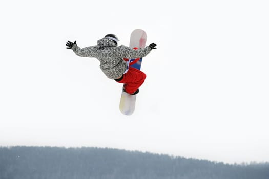 Image of courageous guy jumping on snowboarder in the air