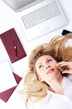 A young woman lying among business objects and chattering on the phone