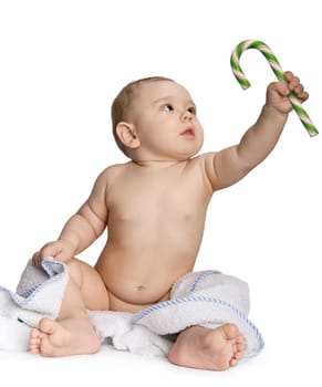 Image of cute baby holding sugar hook and looking at it over white backround