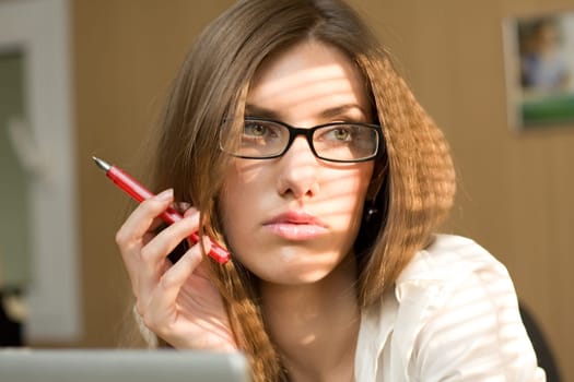 Close-up of serious woman with pen in hand and pensive expression