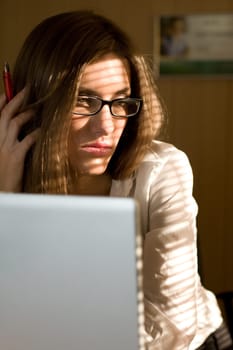 Photo of thinking woman in eyeglasses with laptop near by
