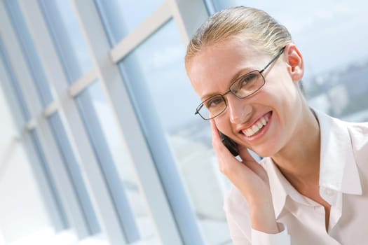 Portrait of pretty business woman talking by mobile phone and looking at camera with smile