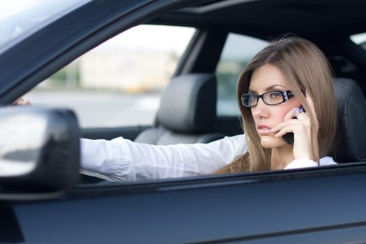 Image of busy woman calling on cellular phone while sitting in her car