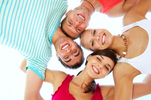 Low angle view of four friends embracing and looking at camera